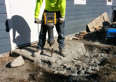 Worker with a jackhammer or pneumatic hammer breaking up a concrete sidewalk