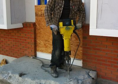 Worker with a jackhammer breaking up a large staircase and entrance