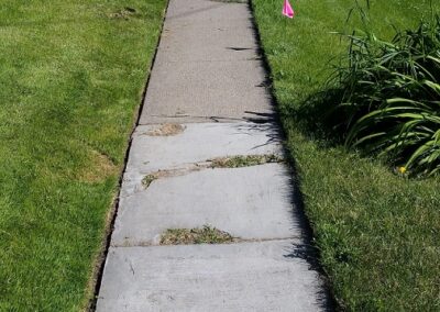 Old concrete sidewalk with large spalling and cracks